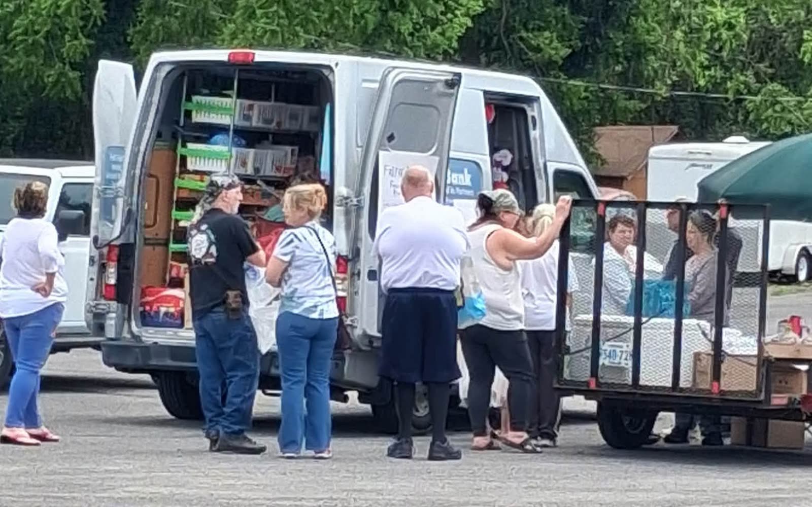 Volunteers unloading groceries from the back of the van and a trailer on a giveaway Saturday